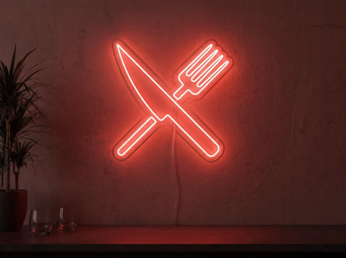 Neonskylt «Gaffel och kniv» i röd LED-neon, monterad på vägg