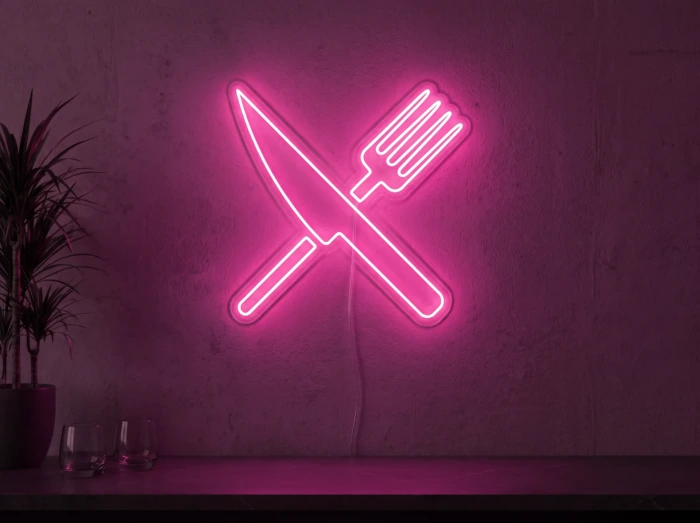 Neonskylt «Gaffel och kniv» i rosa LED-neon, monterad på vägg
