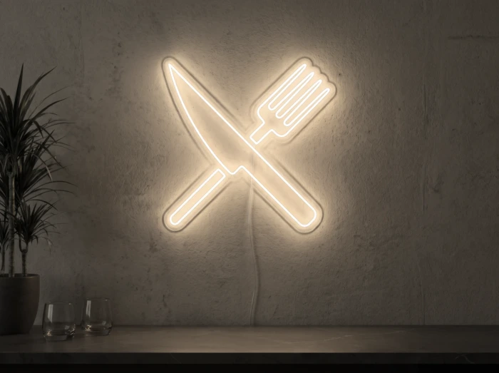 Neonskylt «Gaffel och kniv» i varmvit LED-neon, monterad på vägg