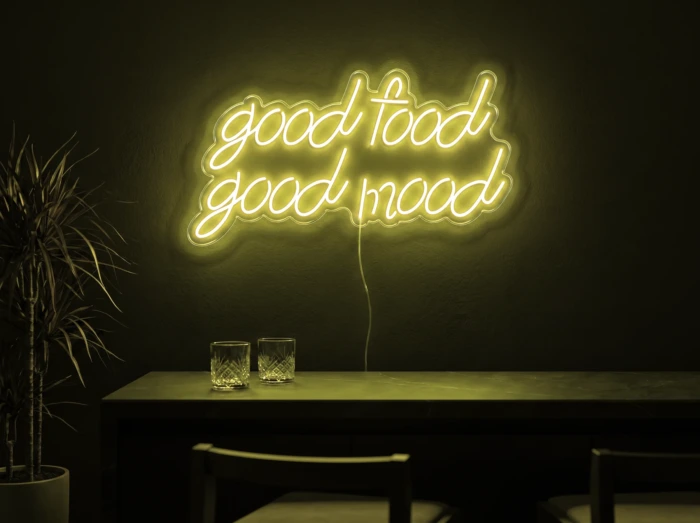 Neonskylt «Good Food Good Mood» i gul LED-neon, monterad på vägg