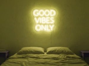 Neonskylt «Good Vibes Only, versaler» i gul LED-neon, monterad på vägg