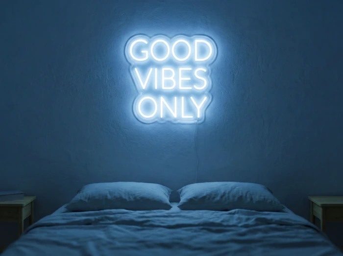 Neonskylt «Good Vibes Only, versaler» i isblå LED-neon, monterad på vägg