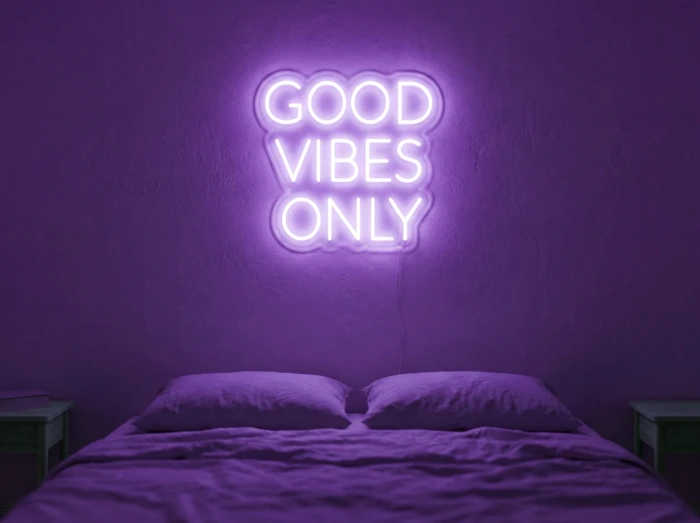 Neonskylt «Good Vibes Only, versaler» i lila LED-neon, monterad på vägg