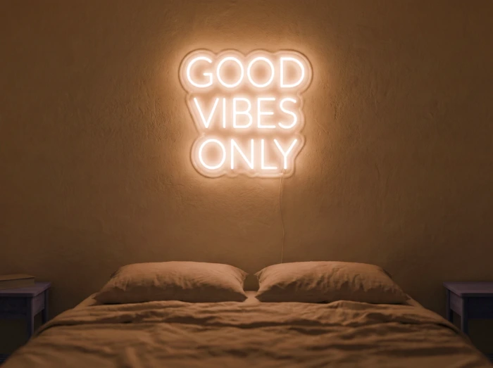 Neonskylt «Good Vibes Only, versaler» i orange LED-neon, monterad på vägg
