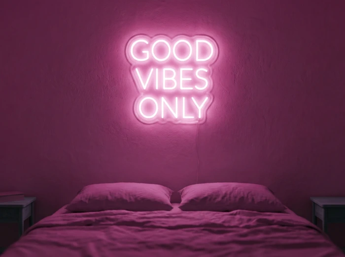 Neonskylt «Good Vibes Only, versaler» i rosa LED-neon, monterad på vägg