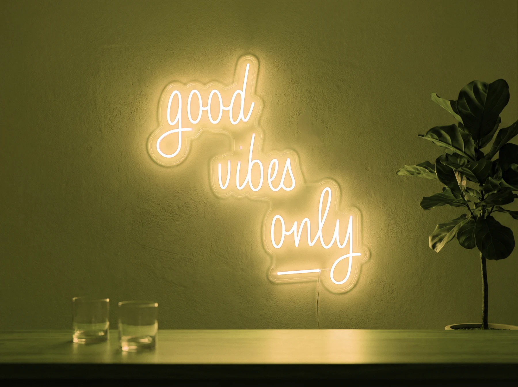 Neonskylt «Good Vibes Only, skrivstil» i gul LED-neon, monterad på vägg
