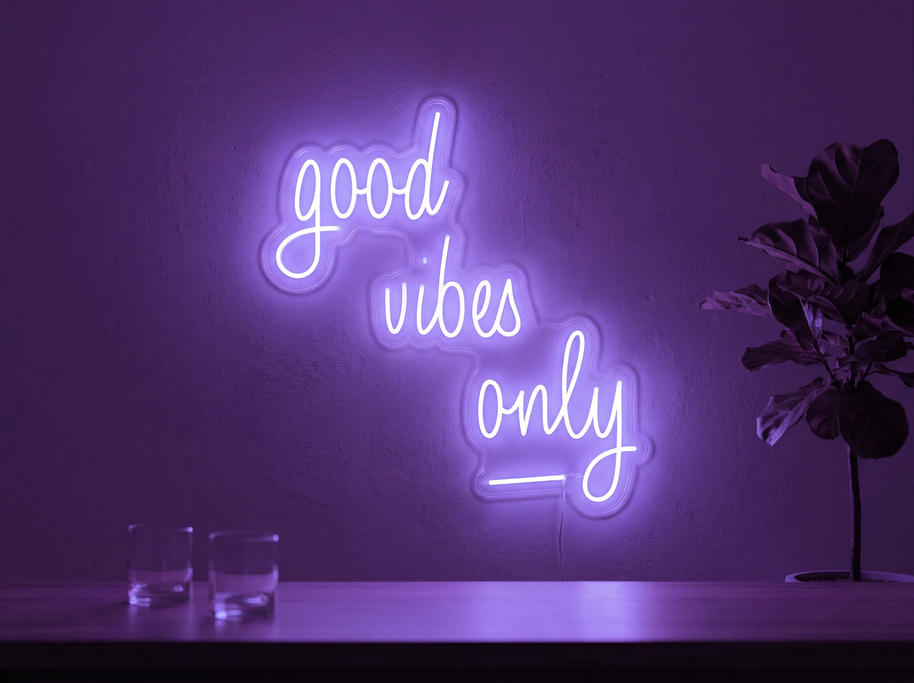 Neonskylt «Good Vibes Only, skrivstil» i lila LED-neon, monterad på vägg