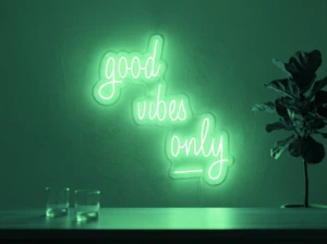 Neonskylt «Good Vibes Only, skrivstil» i mintgrön LED-neon, monterad på vägg