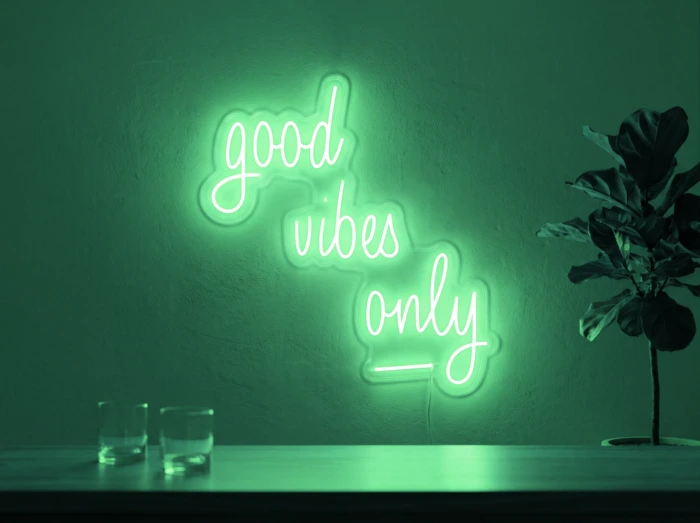 Neonskylt «Good Vibes Only, skrivstil» i mintgrön LED-neon, monterad på vägg