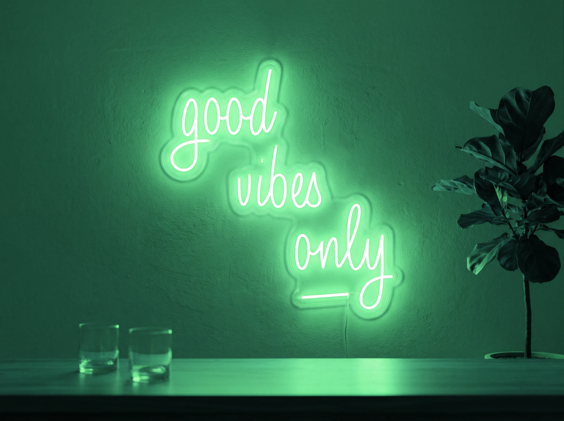 Neonskylt «Good Vibes Only, skrivstil» i mintgrön LED-neon, monterad på vägg