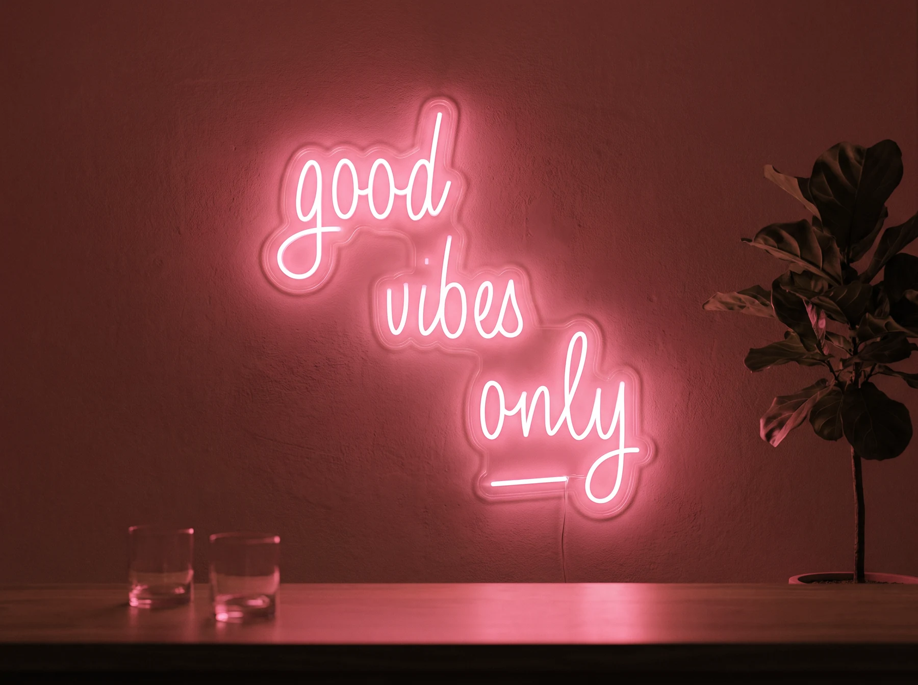 Neonskylt «Good Vibes Only, skrivstil» i röd LED-neon, monterad på vägg