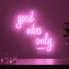 Neonskylt «Good Vibes Only, skrivstil» i rosa LED-neon, monterad på vägg