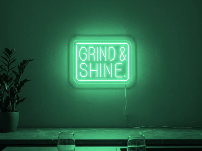 Neonskylt «Grind & Shine» i mintgrön LED-neon, monterad på vägg