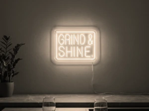 Neonskylt «Grind & Shine» i varmvit LED-neon, monterad på vägg