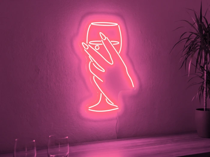 Neonskylt «Hand med glas» i rosa LED-neon, monterad på vägg