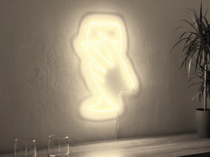 Neonskylt «Hand med glas» i varmvit LED-neon, monterad på vägg