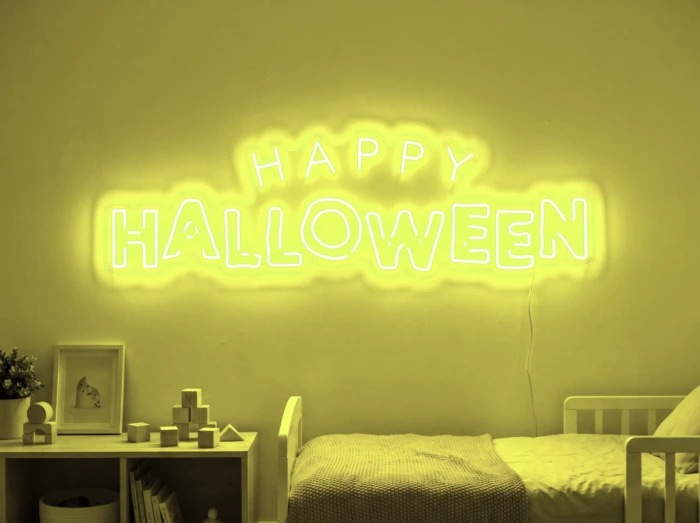 Neonskylt «Happy Halloween» i gul LED-neon, monterad på vägg