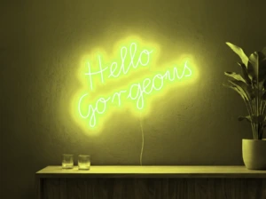 Neonskylt «Hello Gorgeous» i gul LED-neon, monterad på vägg