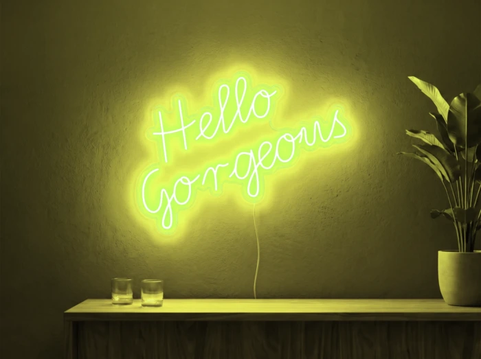 Neonskylt «Hello Gorgeous» i gul LED-neon, monterad på vägg