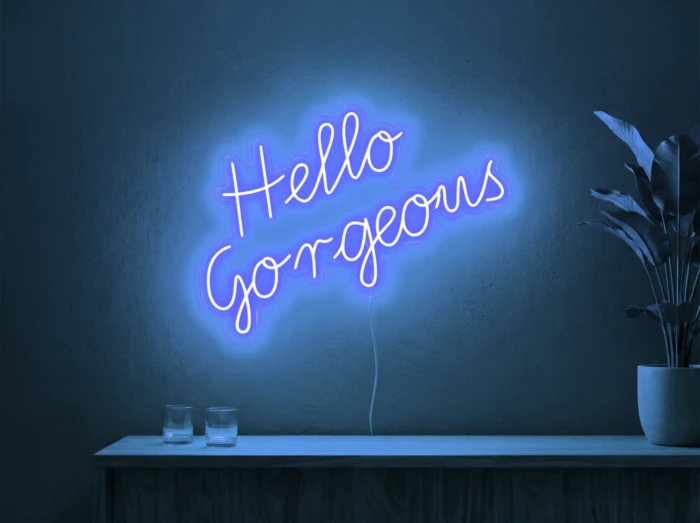 Neonskylt «Hello Gorgeous» i isblå LED-neon, monterad på vägg