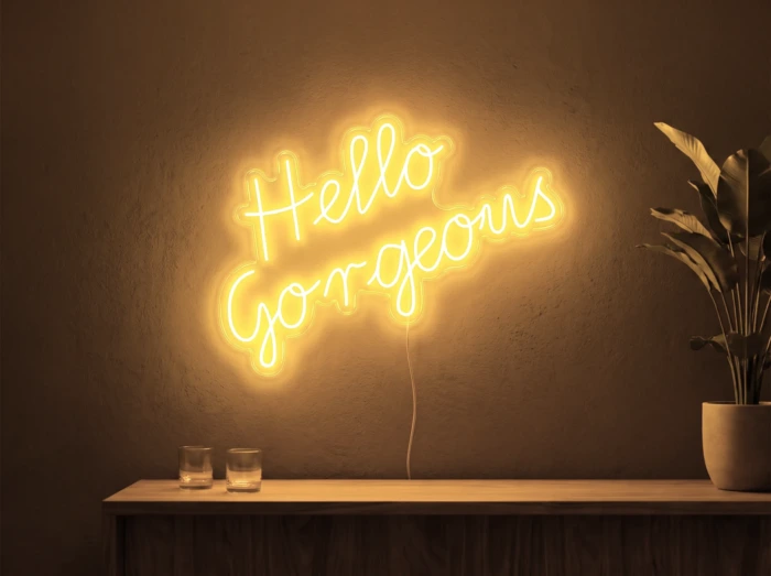 Neonskylt «Hello Gorgeous» i orange LED-neon, monterad på vägg