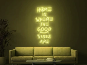 Neonskylt «Home Is Where The Good Vibes Are» i gul LED-neon, monterad på vägg
