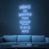 Neonskylt «Home Is Where The Good Vibes Are» i isblå LED-neon, monterad på vägg