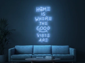 Neonskylt «Home Is Where The Good Vibes Are» i isblå LED-neon, monterad på vägg