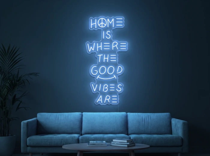 Neonskylt «Home Is Where The Good Vibes Are» i isblå LED-neon, monterad på vägg