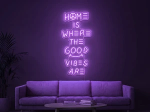 Neonskylt «Home Is Where The Good Vibes Are» i lila LED-neon, monterad på vägg