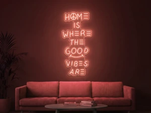 Neonskylt «Home Is Where The Good Vibes Are» i röd LED-neon, monterad på vägg