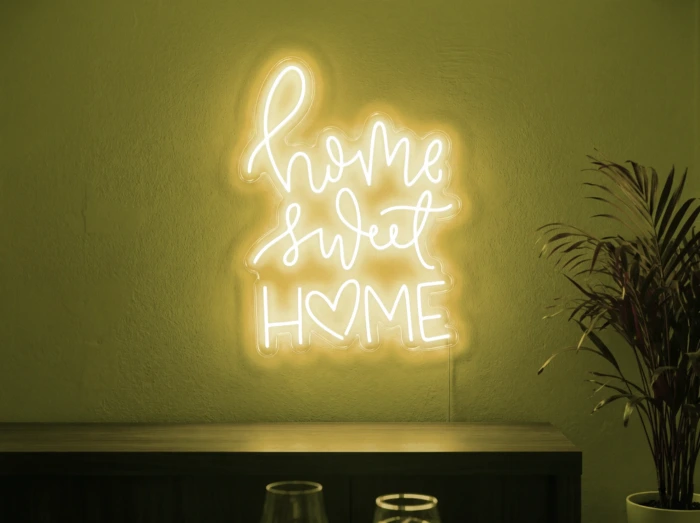 Neonskylt «Home Sweet Home» i gul LED-neon, monterad på vägg
