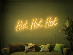 Neonskylt «Hot Hot Hot» i gul LED-neon, monterad på vägg