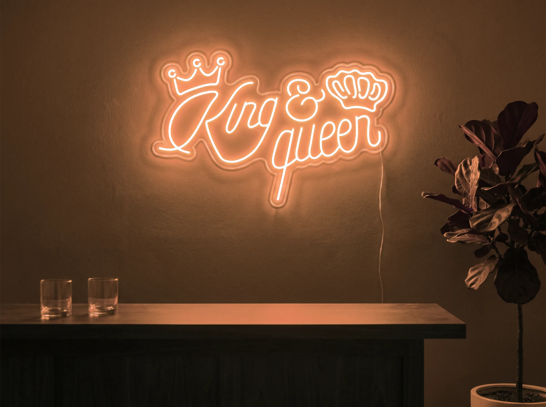 Neonskylt «King & Queen» i orange LED-neon, monterad på vägg