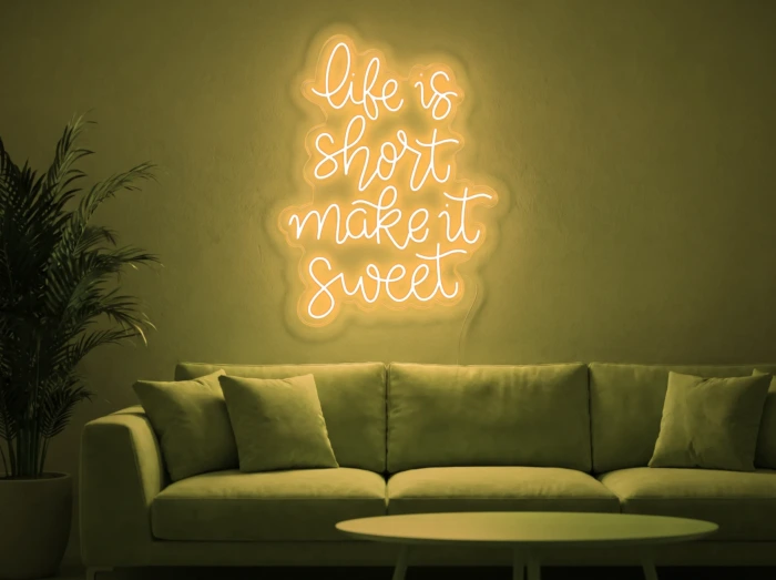 Neonskylt «Life Is Short» i gul LED-neon, monterad på vägg