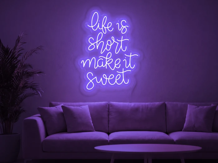 Neonskylt «Life Is Short» i lila LED-neon, monterad på vägg