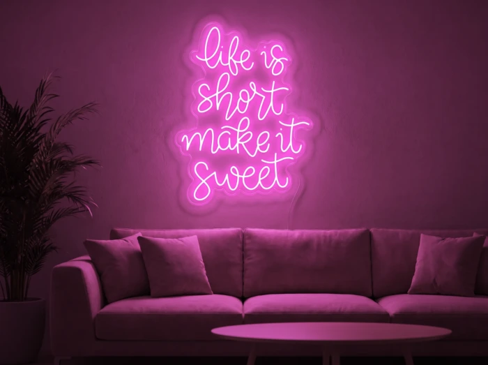 Neonskylt «Life Is Short» i rosa LED-neon, monterad på vägg