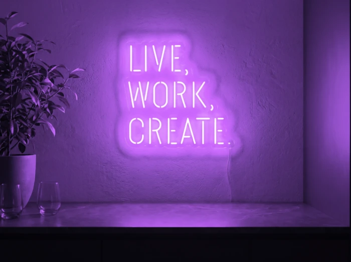 Neonskylt «Live Work Create» i lila LED-neon, monterad på vägg