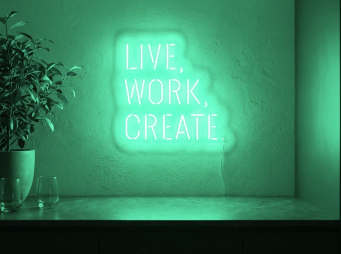 Neonskylt «Live Work Create» i mintgrön LED-neon, monterad på vägg