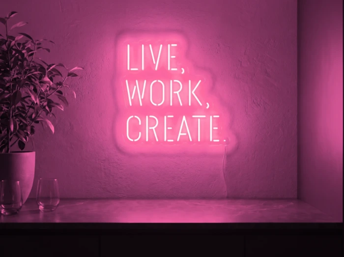 Neonskylt «Live Work Create» i rosa LED-neon, monterad på vägg