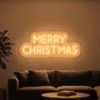 Neonskylt «Merry Christmas, versaler» i orange LED-neon, monterad på vägg