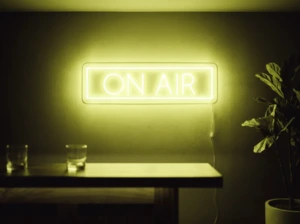 Neonskylt «On Air» i gul LED-neon, monterad på vägg