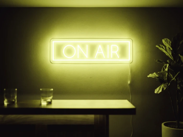 Neonskylt «On Air» i gul LED-neon, monterad på vägg