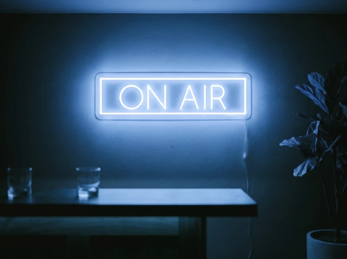 Neonskylt «On Air» i isblå LED-neon, monterad på vägg