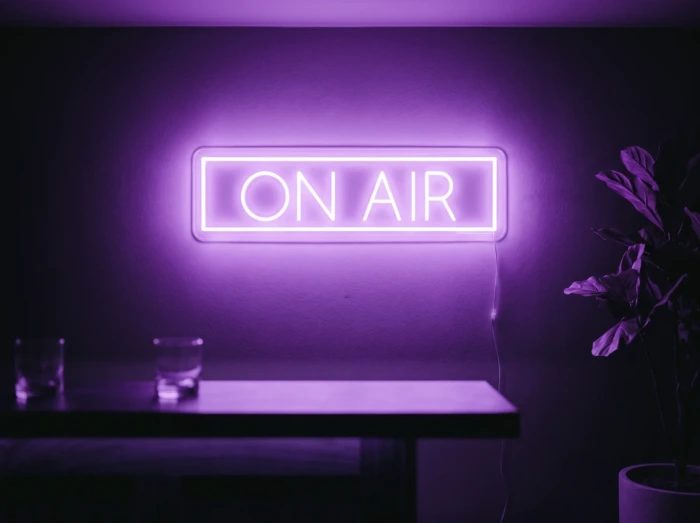 Neonskylt «On Air» i lila LED-neon, monterad på vägg