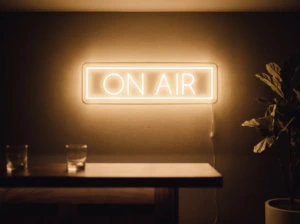 Neonskylt «On Air» i orange LED-neon, monterad på vägg
