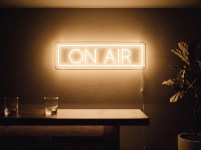 Neonskylt «On Air» i orange LED-neon, monterad på vägg