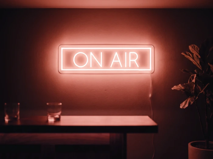 Neonskylt «On Air» i röd LED-neon, monterad på vägg