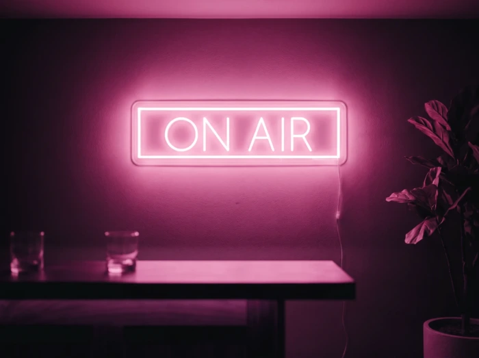 Neonskylt «On Air» i rosa LED-neon, monterad på vägg