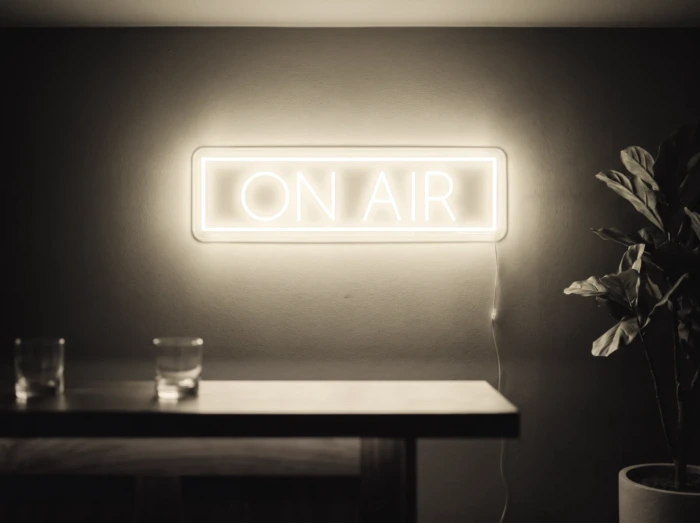 Neonskylt «On Air» i varmvit LED-neon, monterad på vägg